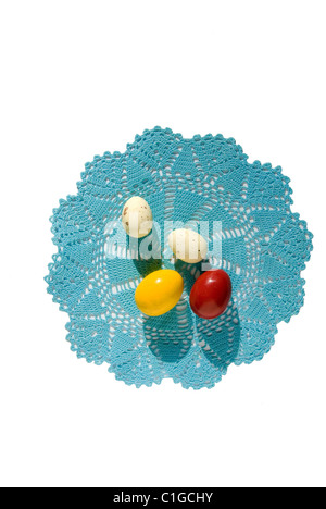 4 Les oeufs de Pâques sur une serviette tricoté bleu isolé sur fond blanc Banque D'Images