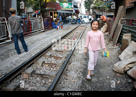 Une jeune fille en rose se promène avec son sac de bonbons à côté de la voie de chemin de fer, Hanoi, Vietnam Banque D'Images