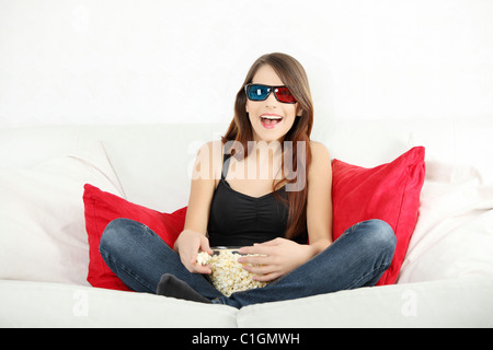 Belle jeune femme regardant la télévision en 3D sans lunettes et eating popcorn Banque D'Images