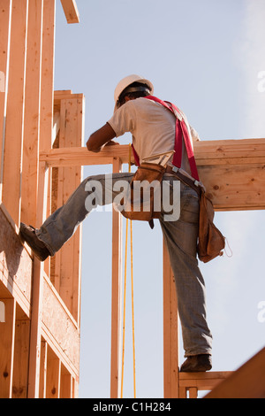 Hispanic carpenter travaillant à l'étage supérieur d'une maison en construction Banque D'Images