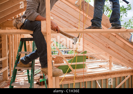 Charpentiers travaillant sur l'Hispanique à l'étage supérieur d'une poutre à une maison en construction Banque D'Images