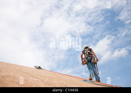 Hispanic carpenter marche sur le toit d'une maison en construction Banque D'Images