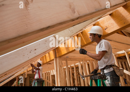 Charpentiers hispaniques travaillant sur chevrons de toit sur une maison en construction Banque D'Images