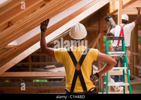 Charpentiers hispaniques travaillant sur poutres du toit sur une maison en construction Banque D'Images