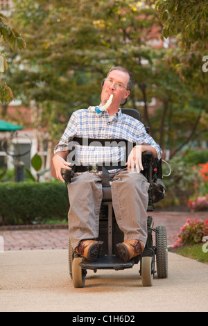 L'homme en fauteuil roulant avec tube respiratoire Banque D'Images