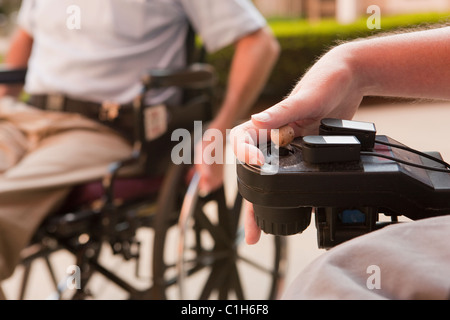 L'homme avec la dystrophie musculaire de Duchenne le contrôle d'un fauteuil roulant motorisé avec mains dégénéré Banque D'Images