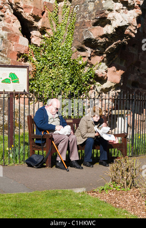 Vieux couple Eating fish and chips sur un banc Banque D'Images