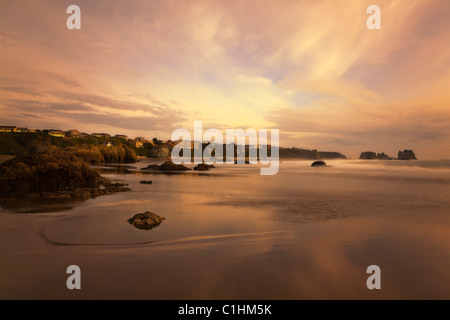 Scenic Bandon Beach Oregon avec soft focus coloré coucher du soleil reflétée dans le sable humide à marée basse et motion floue ondes et nuages Banque D'Images