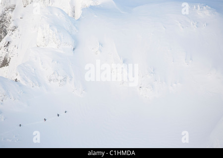 Quatre skieurs de randonnée d'un côté de la montagne pour faire du ski dans l'arrière pays. Banque D'Images