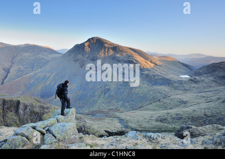 Walker à admirer la vue vers l'aube du soleil sur Grand Gable dans le Lake District Banque D'Images