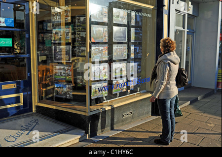 Femme d'âge moyen à la propriété à acheter l'utilisation d'une fenêtre d'agents immobiliers à Buxton UK Banque D'Images