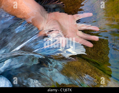 Une main d'homme dans la gestion de l'eau de cours d'eau montrant c'est flux et la clarté Banque D'Images