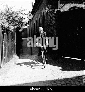 Années 1950, l'été et un homme âgé roulant à vélo sur un chemin pavé en passant devant un panneau indiquant No Cycling, Londres, Angleterre, Royaume-Uni. Banque D'Images