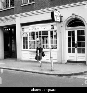 1960s, historique, une dame qui passe devant un Oyster Bar à Shepherd Market, Mayfair, W1 ans, la première à ouvrir ses portes à Londres. Banque D'Images