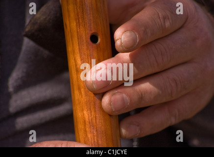 Un gros plan sur une main-d'homme les mains rugueuses, la lecture d'une flûte autochtone en bois. Banque D'Images