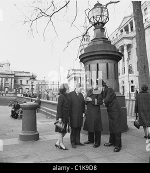 Années 1960. Londres. J Allan Archive de trésorerie. Couple bien habillé demander des directions à partir de deux policiers à Trafalgar Square. Banque D'Images