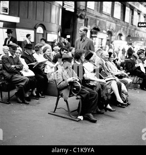 Années 1960. Londres. Différentes générations de gens assis sur des bancs à la gare Victoria de Londres en attente de leur train. Banque D'Images