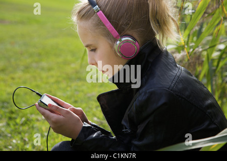 Jeune fille assise à l'extérieur de l'écoute de la musique Banque D'Images