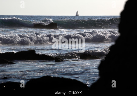 Briser les vagues sur une côte rocheuse avec un voilier à l'horizon, Samara, Péninsule de Nicoya, Costa Rica Banque D'Images