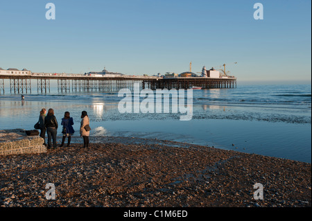 Quatre femmes à la recherche de Brighton Palace Pier à marée basse au début de soleil du printemps. Brighton, East Sussex, Angleterre, Royaume-Uni. Banque D'Images