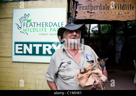 Keith tenant un bébé wallaby en dehors de Featherdale Wildlife Park, près de Sydney, Australie Banque D'Images
