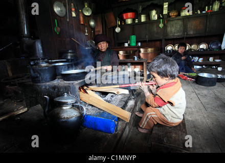 Petit garçon d'allumer un feu dans une maison traditionnelle dans le Népal Himalaya népalais hills Banque D'Images