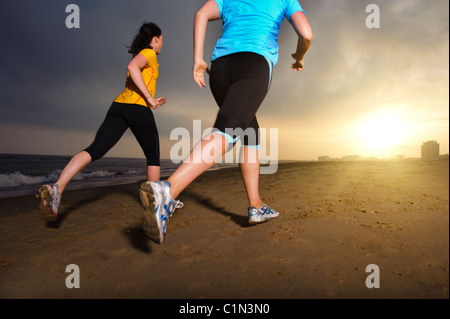 Les femmes jogging on beach at Dusk Banque D'Images