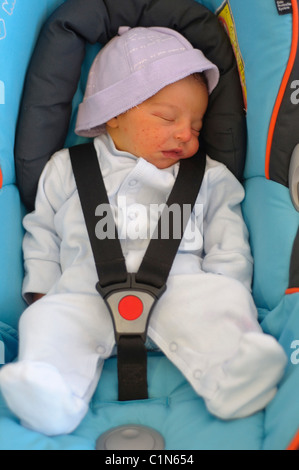 Bébé garçon endormi attaché sur un siège de voiture Banque D'Images