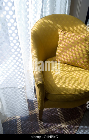 Fauteuil jaune tacheté par rideau sur tapis style tartan Banque D'Images