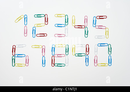 Les nombres de zéro à neuf fait avec des trombones multicolores photographié sur fond blanc Banque D'Images