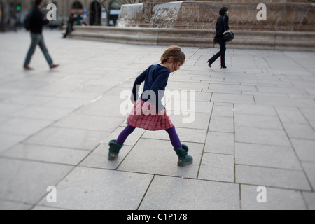 Girl playing hopscotch près d'une fontaine publique de Paris France Banque D'Images