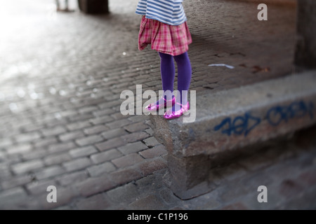 Fille debout sur un banc de parc en béton avec graffiti pulvérisé "tagged" Banque D'Images