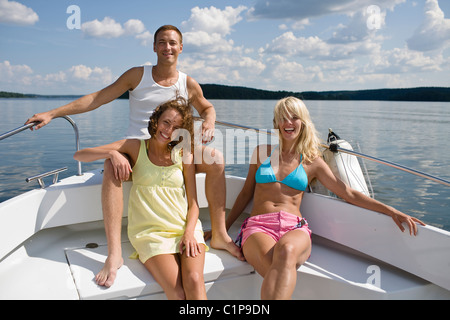 Deux jeunes femmes et young man sitting in location sur le lac Banque D'Images