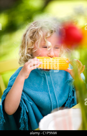 Fille de manger des épis de maïs à l'extérieur Banque D'Images