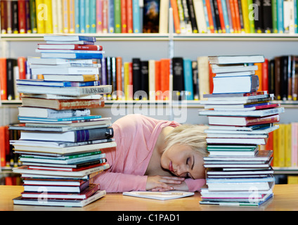 Jeune femme entourée par books in library Banque D'Images