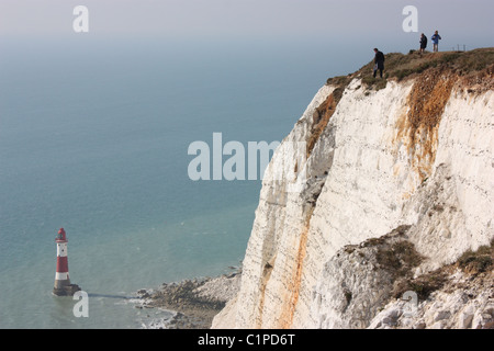 L'Angleterre, Beachy Head, les gens en haut de falaise blanche avec phare ci-dessous Banque D'Images