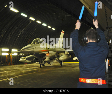 Un chef d'équipe du 52e Escadron de maintenance des aéronefs marshals un F-16 Fighting Falcon à l'appui de l'opération Odyssey Dawn. Banque D'Images