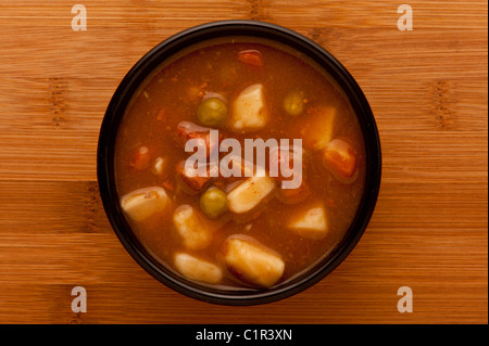 Déposez une dose de soupe de légumes épaisse dans un bol en céramique noire sur une table en bois. Banque D'Images