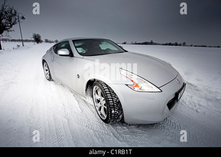 Voiture de sport bloquée dans un champ enneigé avec des chenilles de pneus au sol. Banque D'Images