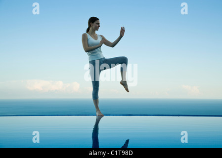 Woman practicing Tai Chi Chuan sur le bord de piscine à débordement Banque D'Images