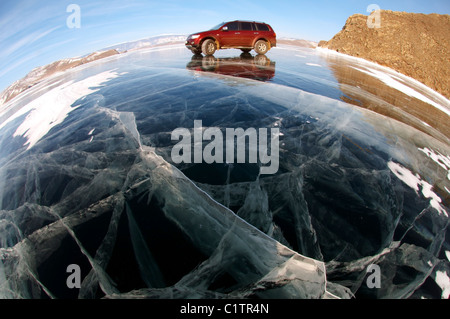 Voiture rouge sont à l'origine le long de la glace d'un lac gelé. Le lac Baïkal, l'île Olkhon, Sibérie, Russie Banque D'Images