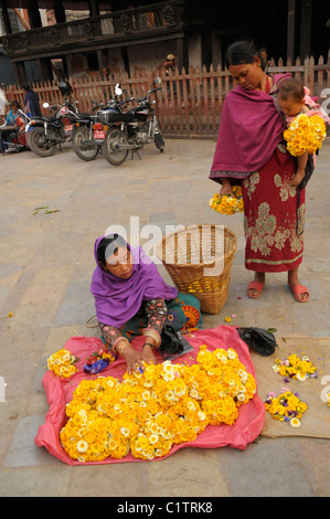 Dame holding baby acheter des fleurs pour faire du mérite, Katmandou, Népal Banque D'Images
