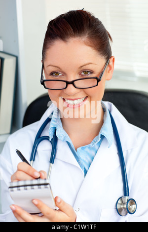 L'auto-assurance female doctor smiling at the camera holding un bloc-notes Banque D'Images