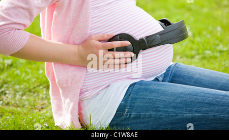 Femme enceinte mettant son écouteur sur son ventre Banque D'Images