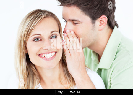 Bel homme murmurer quelque chose à son amie sur un fond blanc. Banque D'Images