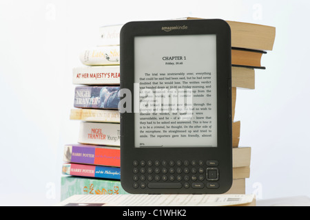 Un lecteur de livre électronique Amazon Kindle et une pile de livres de poche sur un fond blanc. Le Kindle 3 modèle. Pour un usage éditorial uniquement Banque D'Images