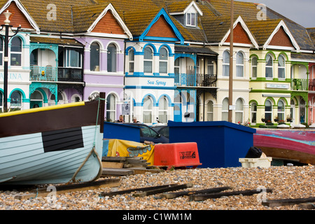 Maisons en bord de mer aux couleurs vives à Worthing, Angleterre avec des bateaux sur la plage à l'avant-plan Banque D'Images