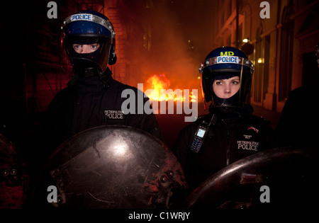 Mars 26/03/2011 Anti-Cuts, Londres, la police montent la garde sur Jermyn St comme le feu mis par les manifestants fait rage dans la distance. Banque D'Images