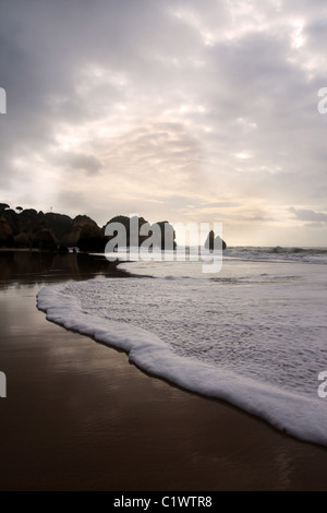 Plage rocheuse dans village Alvôr en Algarve, Portugal avec une vague baignant la côte. Banque D'Images