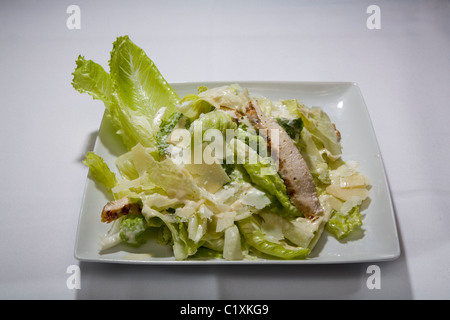 Salade de poulet aux légumes vert laitue plaque carrée blanche cuisine légère méditerranéenne alimentaire vinaigrette nappe lumière appétit mea Banque D'Images